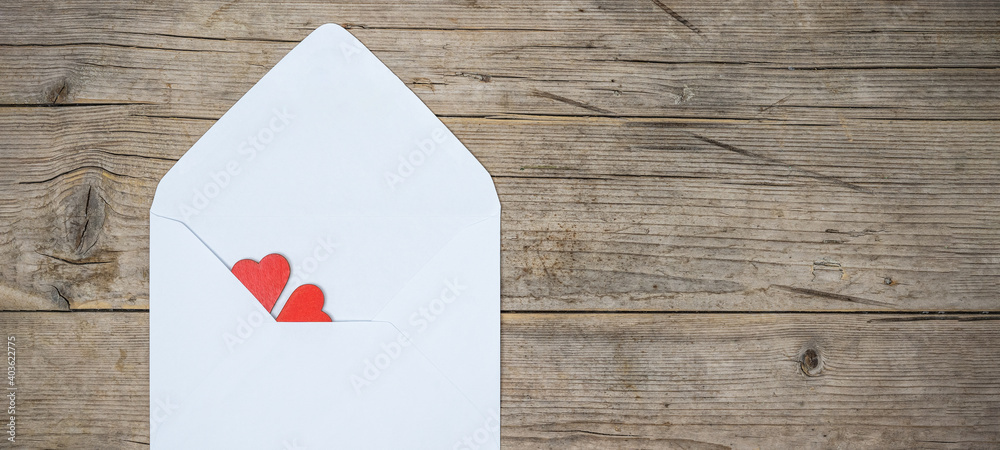Valentines day  love wedding greeting card concept. White envelope with red hearts on rustic brown wooden wood table texture background top view. Flat lay.
