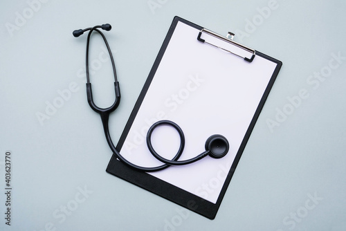 фотографія Black stethoscope and blank medical form on grey background