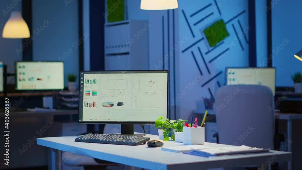 Empty start up business office with modern design during night with graphics running on the desktop. Financial company with nobody in it, place of work startup, workplace indoors concept Empty start up business office with modern design during night with graphics running on the desktop. Financial company with nobody in it, place of work startup, workplace indoors concept