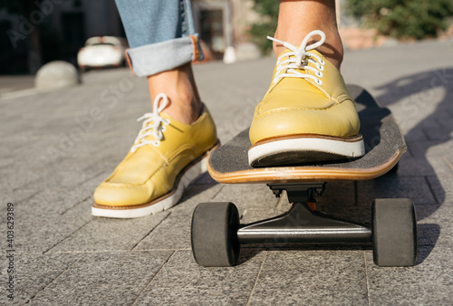 Close up of man legs in stylish yellow shoes riding a skateboard. Active lifestyle concept 