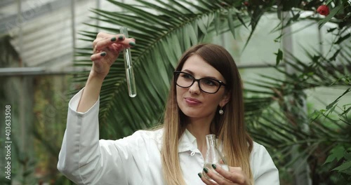 Female scientist biologist researcher testing seedling plant test tube lab. Biological agriculture research genetic engineering laboratory, seeds food farming GMO geneticaly modified food. 4 K slow-mo photo