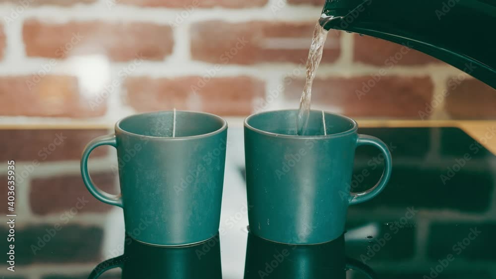 Making tea for two people. Pouring hot water into green tea cups