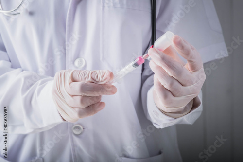 Coronavirus vaccine and development and creation COVID-19 vaccine concept.Doctor hand in gloves hold medical vaccine bottles dose and syringe ready to treat the patient.