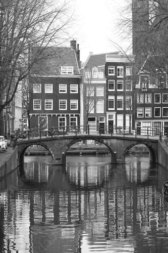 Canal View with Houses, Bridge and Reflections in Amsterdam in Black and White