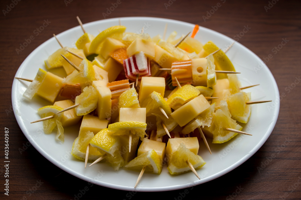 Canapes with cheese, lemon and marmalade on a white plate. Wooden table background. Fresh and healthy food. Diet Canapes with cheese, lemon and marmalade on a white plate. Wooden table background. Fresh and healthy food. Diet