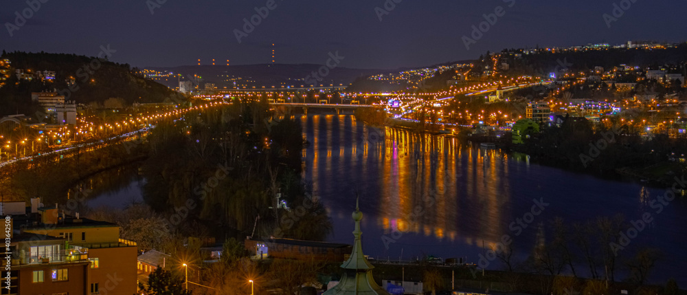 Night cityscape of Prague with reflections on a river.