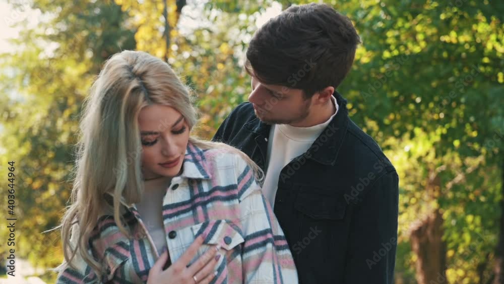 Romantic man kisses girlfriend on the cheek. Young couple hug and kiss outdoors. Slow motion Romantic man kisses girlfriend on the cheek. Young couple hug and kiss outdoors. Slow motion