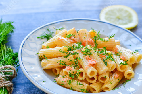  Italian home made  macaroni pasta with smoked salmon , creamy sauce and fresh dill on wooden background