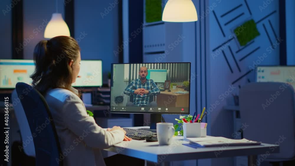 Businesswoman having corporate meeting with remotely paralyzed man using webcam sitting in start up business office working overtime late at night. Manager talking on video conference at midnight Businesswoman having corporate meeting with remotely paralyzed man using webcam sitting in start up business office working overtime late at night. Manager talking on video conference at midnight