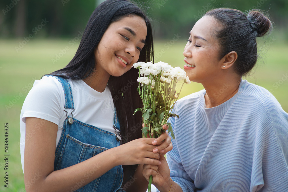 Obraz premium Asian teenager daughter gives her bouquet of flowers to her mother at park, Happy mother's day