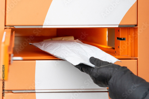 Woman recieve parcel in automated self service post terminal and parcel storage machine outdoors