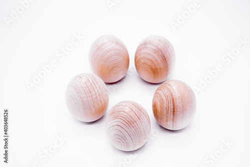 Five hand-made unpainted wooden eggs on a white background