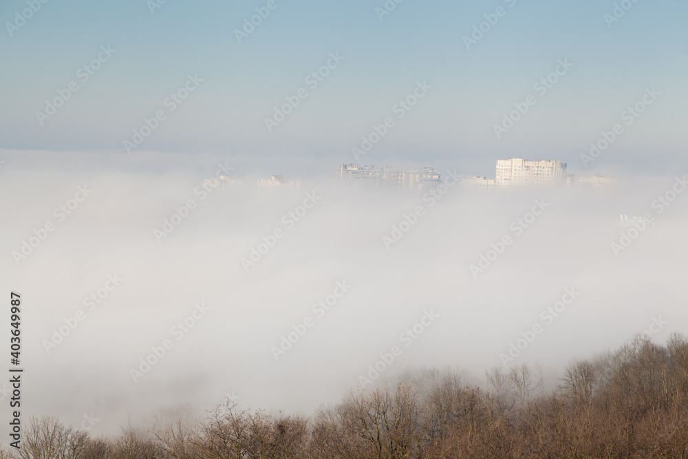 Roofs of buildings in the fog with blue sky