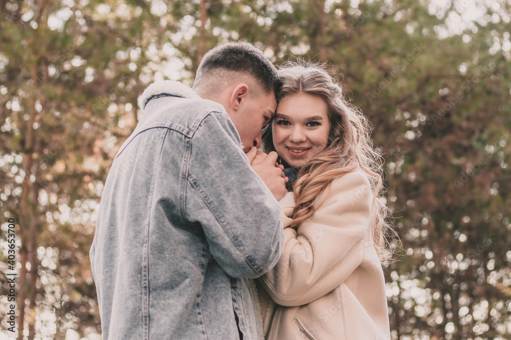 Obraz premium the guy holds the girl's hands and kisses them and the girl smiles while in the pine forest in winter