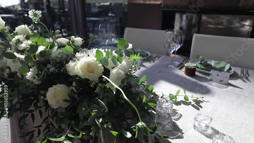 Flower arrangement for summer wedding, made of roses and green branches on a dinner table in the restraunt