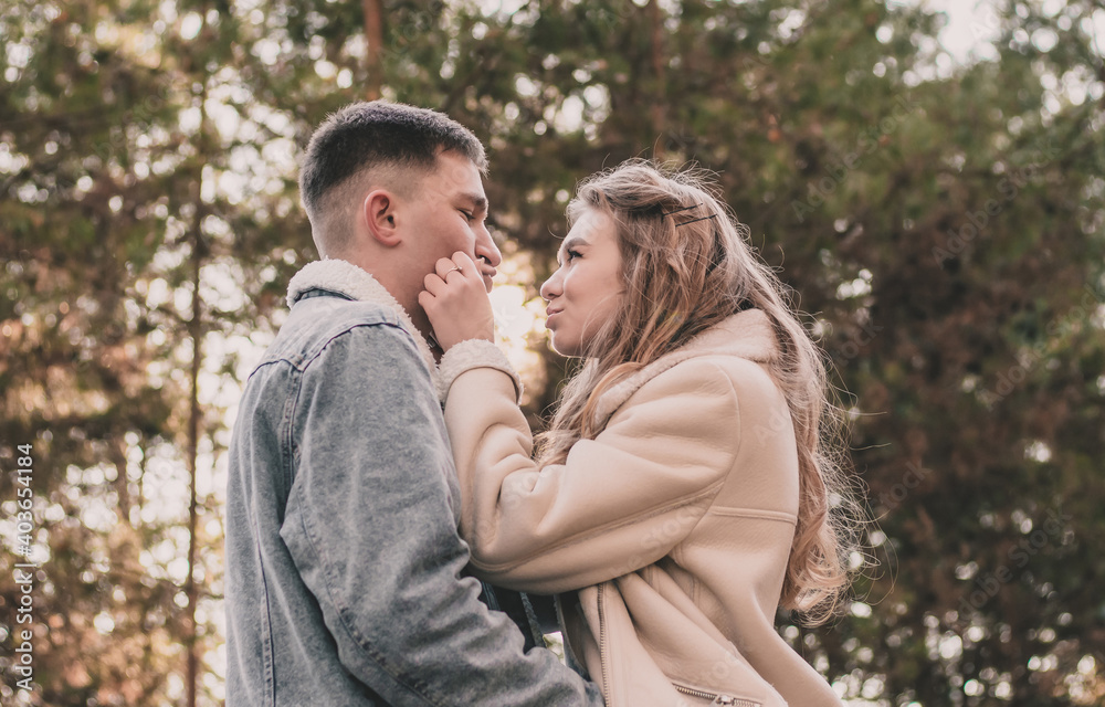 A girl holds a guy by the face with her hands and smiles at him while walking in a pine forest A girl holds a guy by the face with her hands and smiles at him while walking in a pine forest