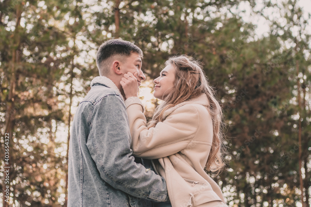A girl holds a guy by the face with her hands and smiles at him while walking in a pine forest A girl holds a guy by the face with her hands and smiles at him while walking in a pine forest