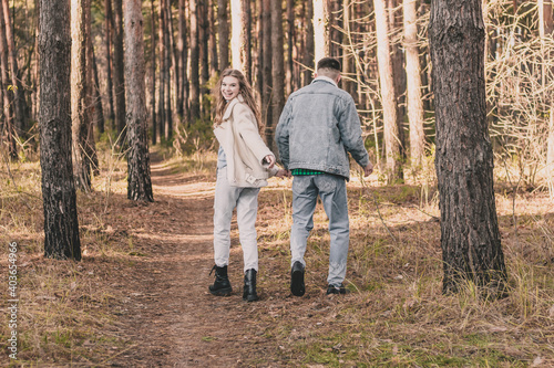  the guy hugs the girl tightly and kisses her on the cheek while in the pine forest