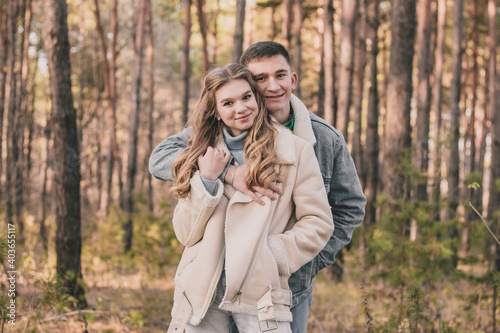  the guy hugs the girl and smiles in the pine forest