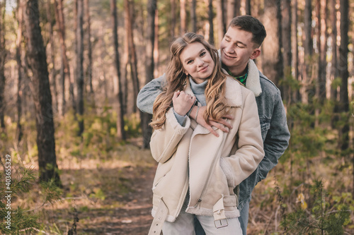  the guy hugs the girl and smiles in the pine forest