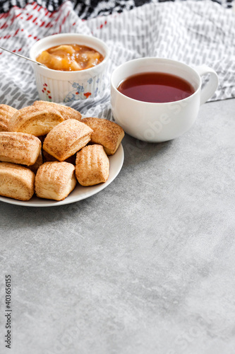 Tasty breakfast. Homemade sweet cinnamon cookies and cup of tea. Apple confiture on background © tynza