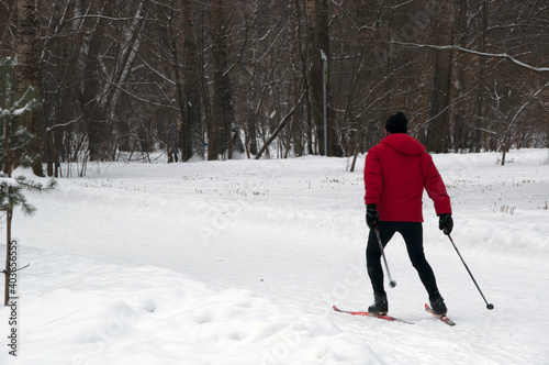 Winter. A man in a red jacket is skiing in the park. © Viacheslav