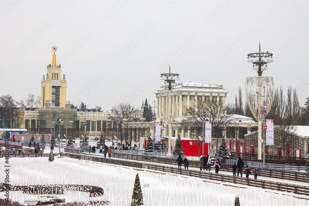 panoramic view of vdnkh Park with historical palaces pavilions and New Year decorations and people walking on a cloudy winter day and space for copying in Moscow Russia