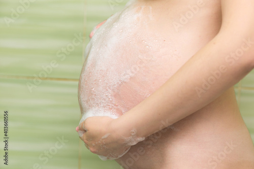 pregnant girl washes her belly in the shower