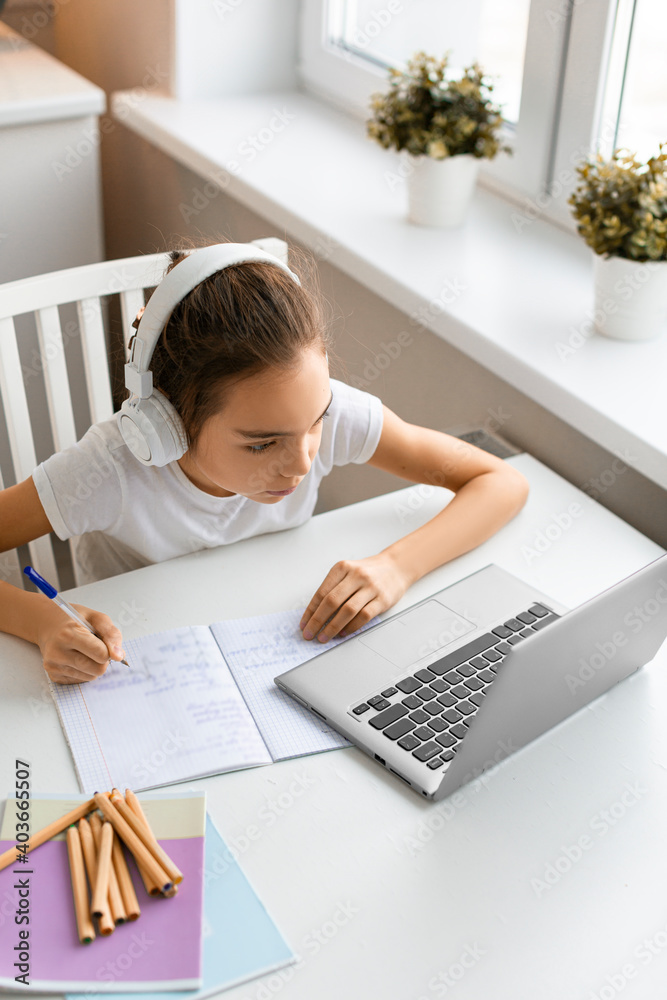 Top view of a teenager girl doing homework at home in front of a laptop monitor. Top view of a teenager girl doing homework at home in front of a laptop monitor.