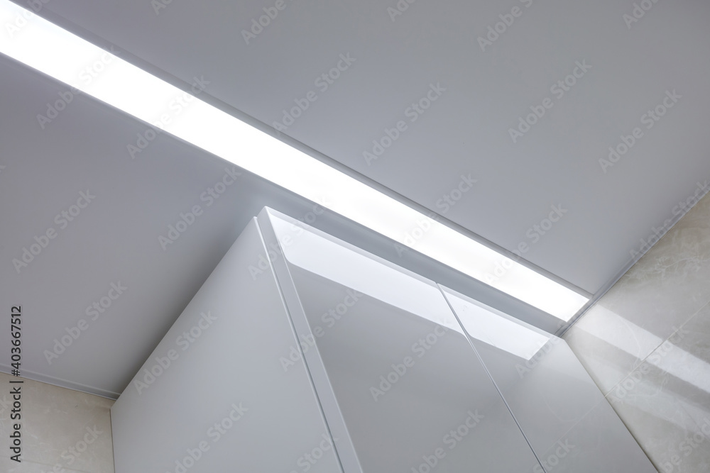 suspended ceiling with halogen spots lamps and drywall construction in empty room in apartment or house. Stretch ceiling white and complex shape.