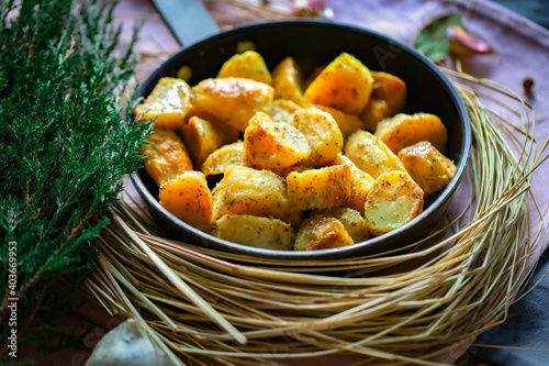 Przypieczone smaczne ziemniaki na patelni z ziołami. Fotografia kulinarna, tło naturalne, wiejski klimat