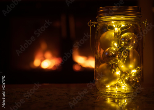 Bolas doradas dentro de un frasco de cristal con una chimenea de fondo