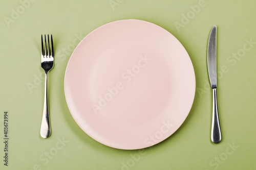 Knife, plate and fork on a green background.
