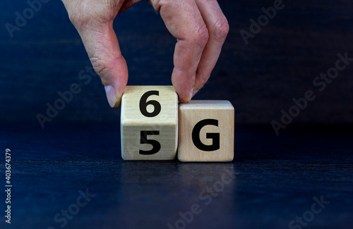 Time to 6G symbol. Male hand turns wooden cube and changes sign 5G to 6G. Technology, business, network, communication and 6G concept. Beautiful dark wooden background, copy space. photo