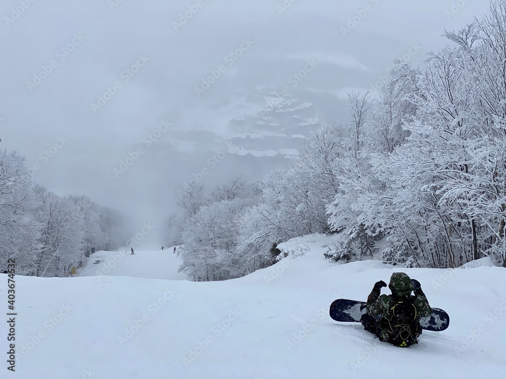 Snowboarders sitting on the trail looking down to beautivul panorama valley of Stowe Mountain Ski resort Snowboarders sitting on the trail looking down to beautivul panorama valley of Stowe Mountain Ski resort