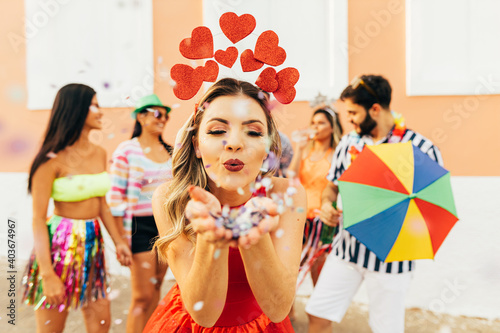 Brazilian Carnival. Young woman enjoying the carnival party blowing confetti photo