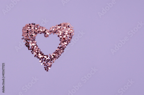 Heart shaped frame made of shiny sequins on a blue background. Festive texture for Valentines Day, Mothers Day, Womens Day, day of the wedding and Birthday. Banner, Flatlay, copy space.