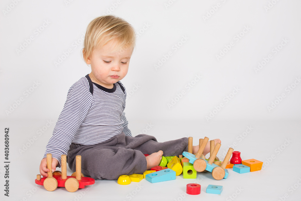 Small baby boy is playing with colourfull wooden block isolated on white background. Creativity concept with copy space. Small baby boy is playing with colourfull wooden block isolated on white background. Creativity concept with copy space.