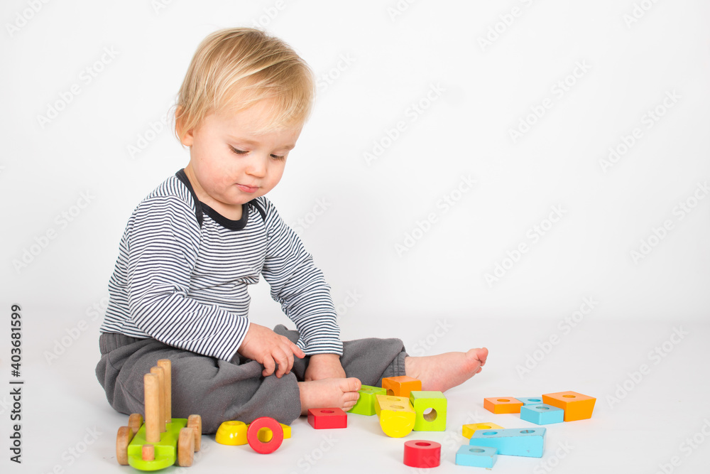 Little baby boy is playing with colourfull wooden block isolated on white background. Education and learn game concept with copy space. Little baby boy is playing with colourfull wooden block isolated on white background. Education and learn game concept with copy space.