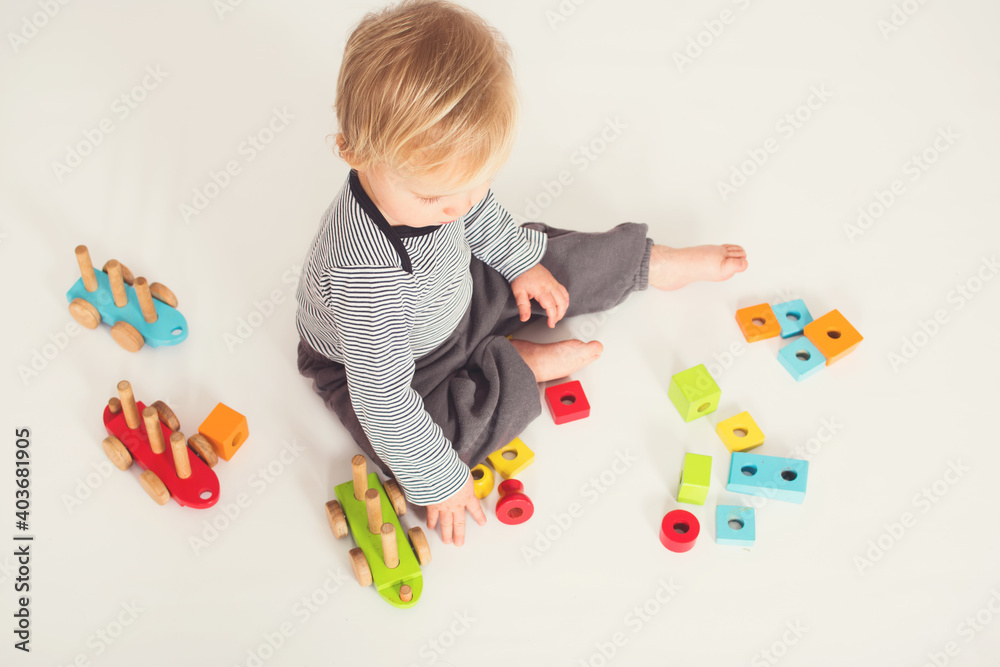 One year old baby boy is playing with colorful wooden block isolated on white background in studio. Top view. One year old baby boy is playing with colorful wooden block isolated on white background in studio. Top view.