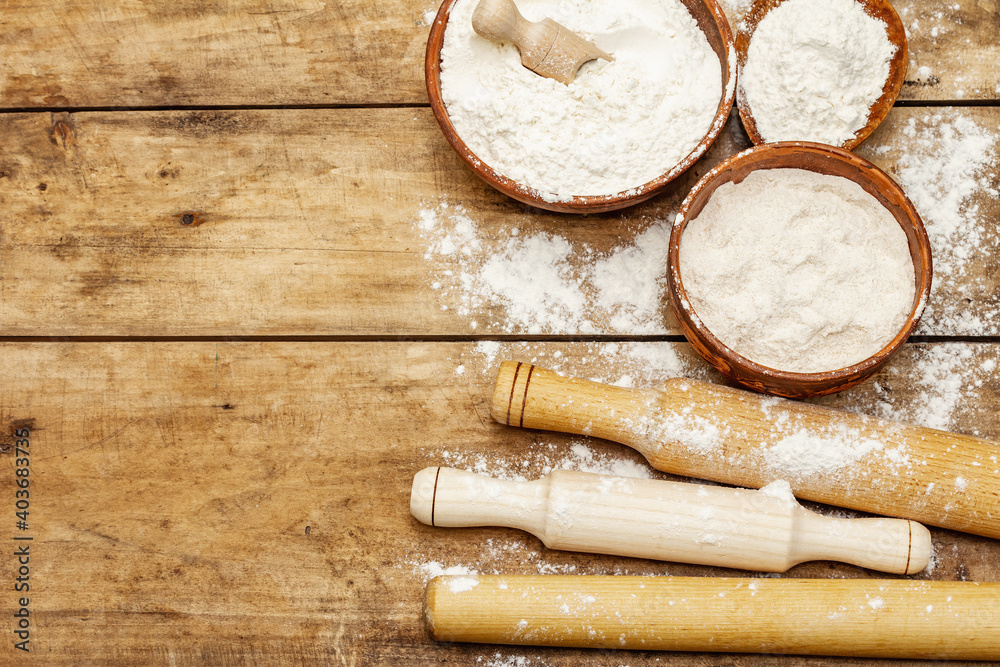 Ingredients for baking bread: bowls of flour and rolling pins Ingredients for baking bread: bowls of flour and rolling pins