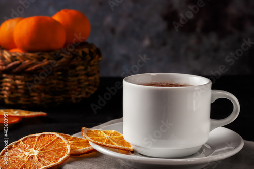 Cup of tea with dried orange slices on black wooden background