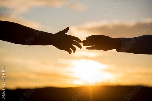 Outstretched hands, salvation, help silhouette, concept help. Giving a helping hand. Rescue, helping gesture or hands. Two hands silhouette on sky background, connection or help concept