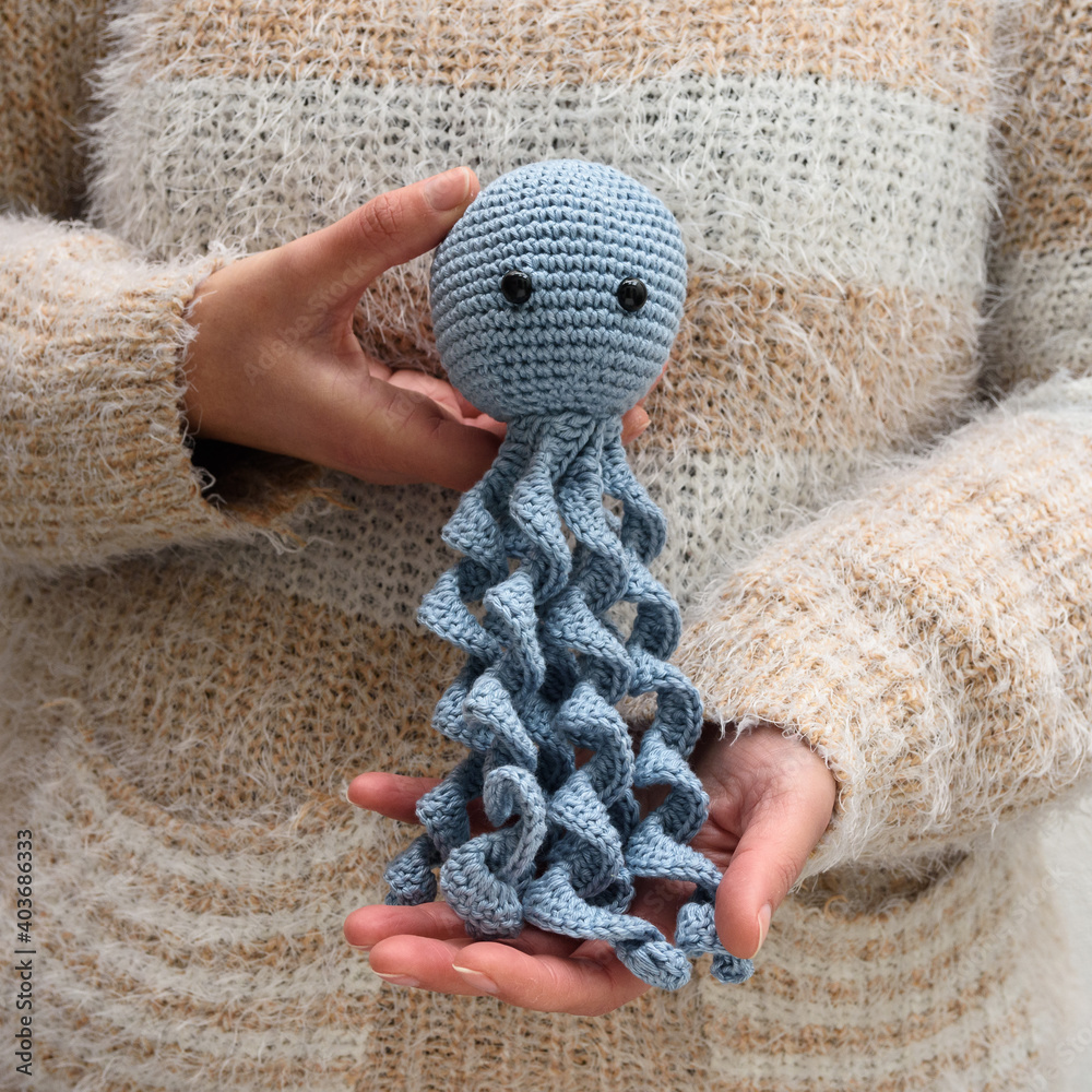 Polvo de pelúcia azul, feito na técnica de crochê amigurumi sendo segurado  por uma pessoa. Stock Photo | Adobe Stock