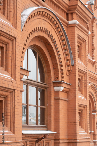 A vaulted window in a red brick wall covered with snow, Moscow