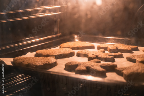 Christmas cookies baking in the oven. Christmas baking. Gingerbread biscuits on baking tray.