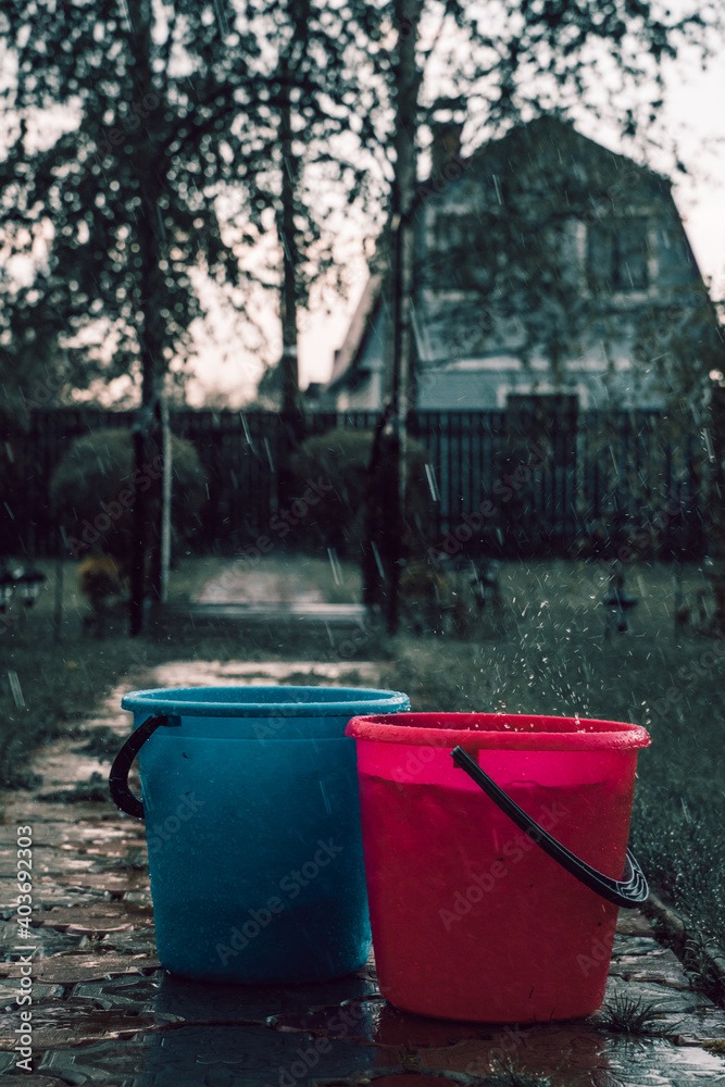 Two plastic buckets - red and blue in the rain Two plastic buckets - red and blue in the rain