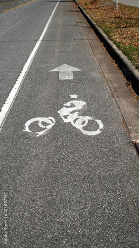 Scratched, old looking bike lane symbol on the road with arrow