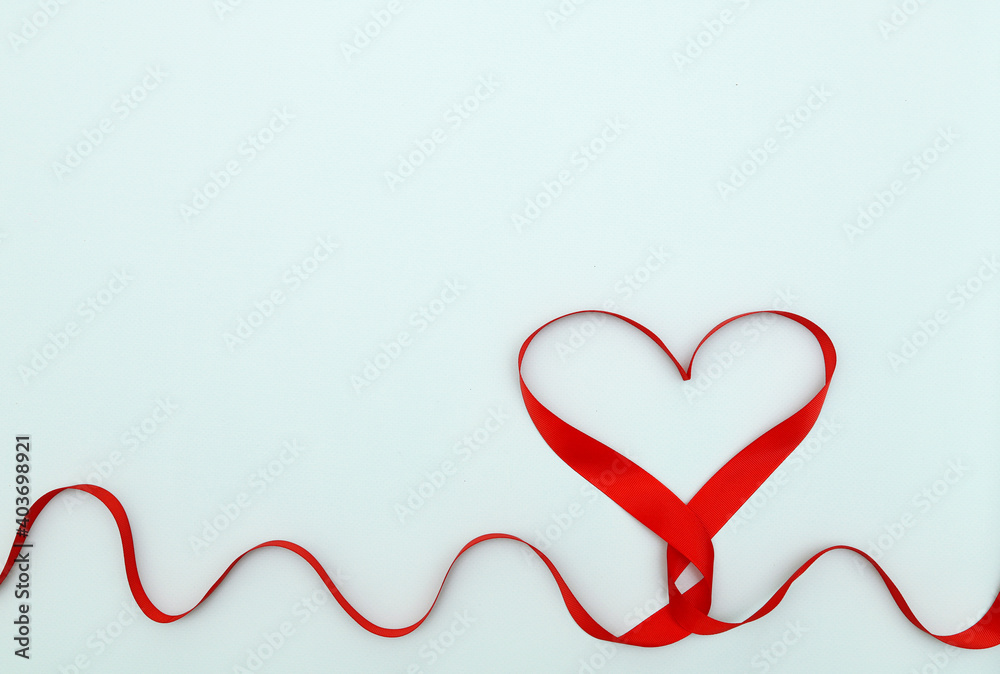 Heart made of red ribbon on a blue background. Concept: Creative Valentine's Day. the rhythm of the cardiogram.copy space