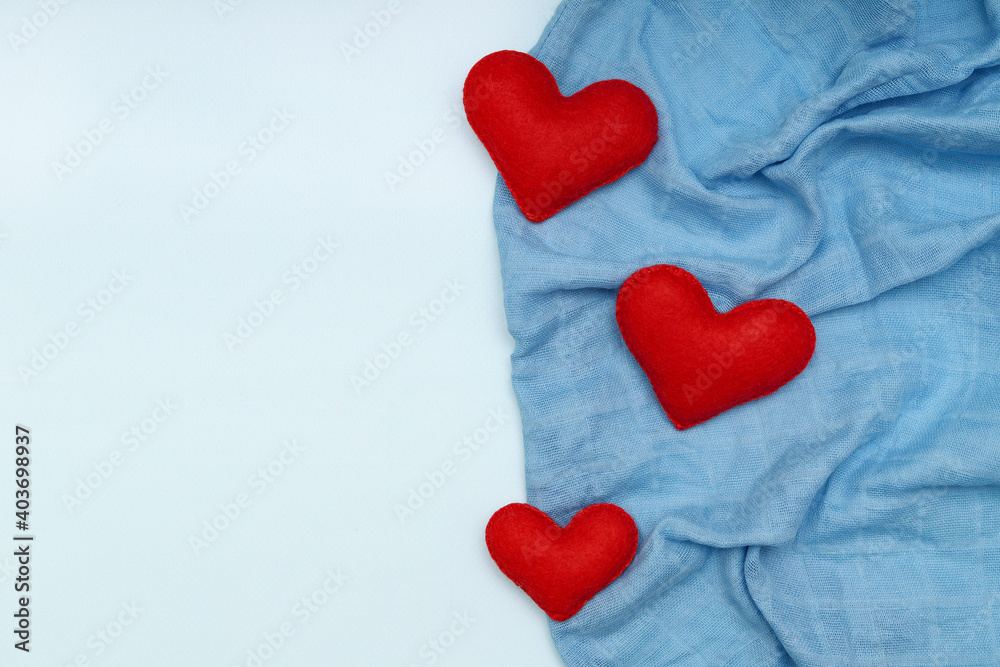 Obraz premium Layout with red hearts sewn from felt on blue fabric with space for text. The concept of Valentine's day.